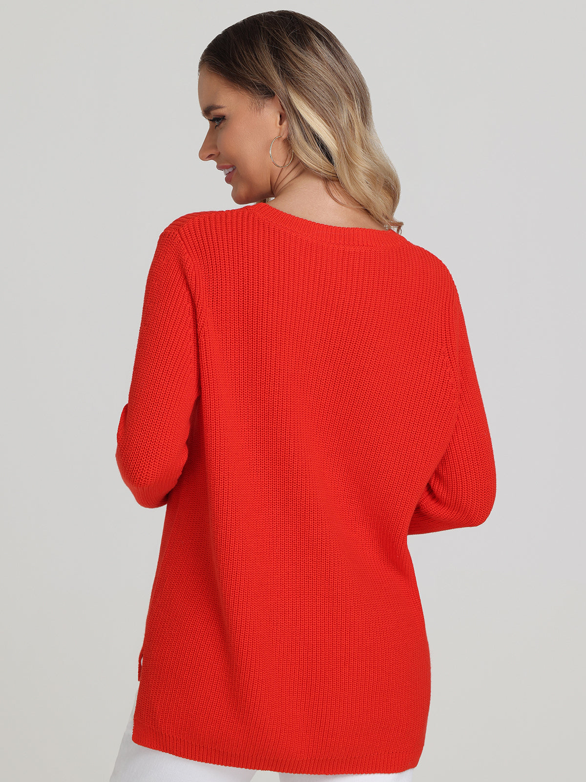 A person with shoulder-length hair is shown wearing a relaxed-fit bright red sweater from 525 America. As they turn slightly, looking over their shoulder against a plain light backdrop, the sweaters versatile style shines through.