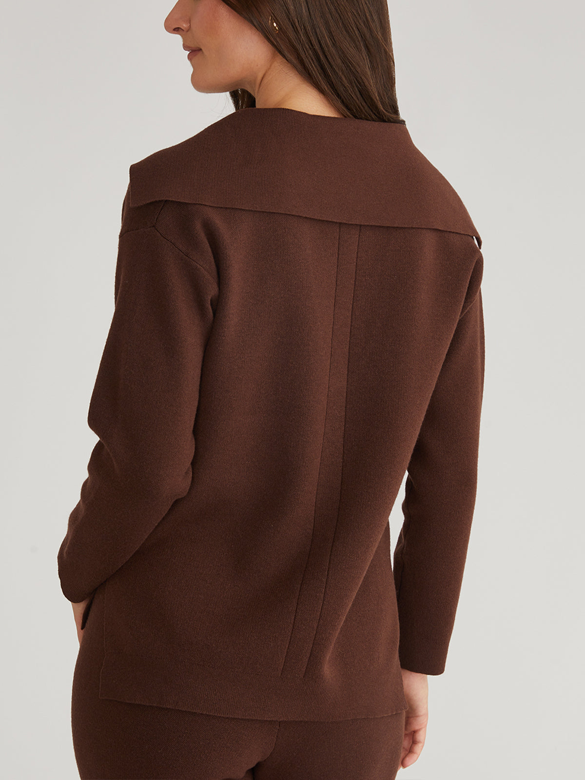 A person with long dark hair models a chic brown long-sleeve top and matching pants from 525 America, perfect for a stylish winter look. Captured from the back against a plain background, this ensemble embodies elegance and simplicity.